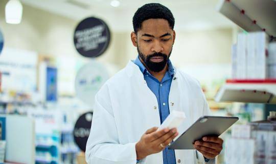 man in lab coat examines medicine box