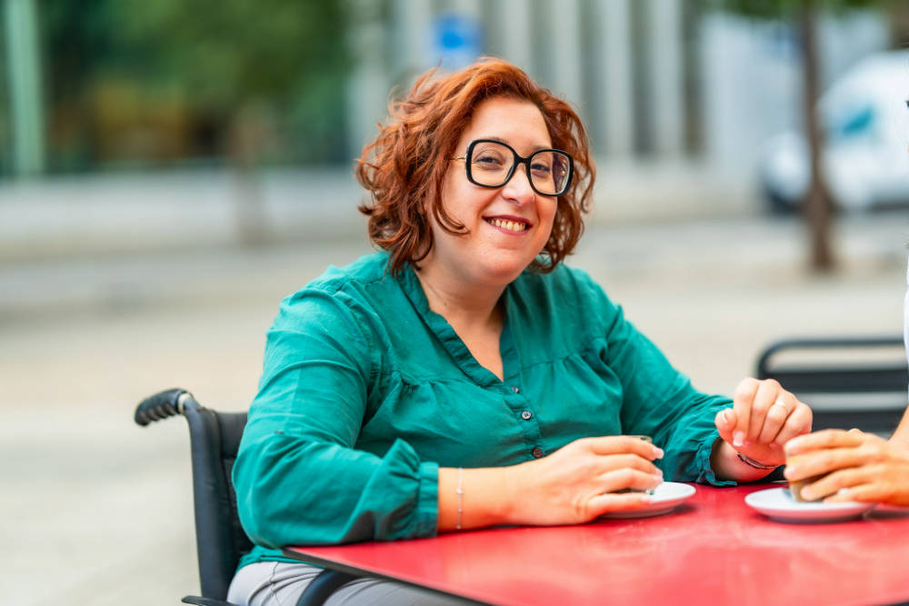 Women drinking coffee in wheelchair while smiling