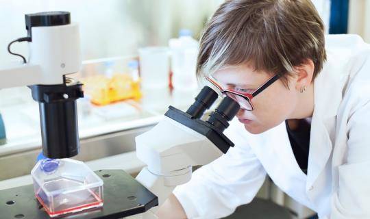 woman looking through microscope