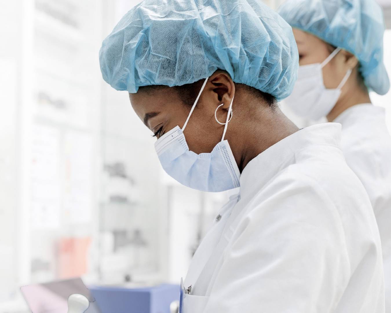 Two female scientists working in a laboratory wearing protective gear