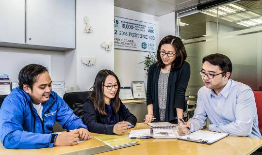 Four World Courier associates gather around a conference table in a meeting room.