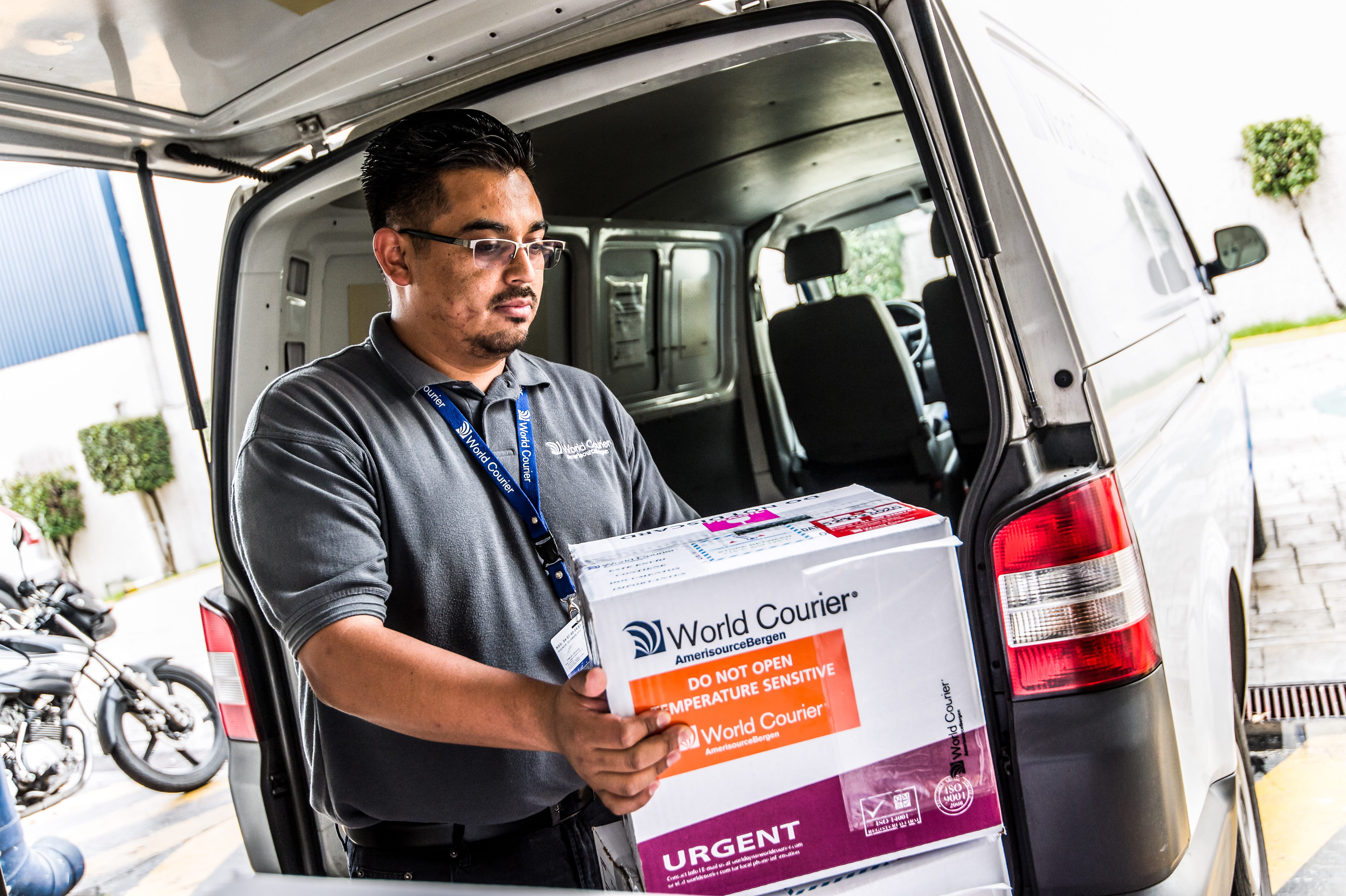 A World Courier driver unloads a box out of the back of his van.