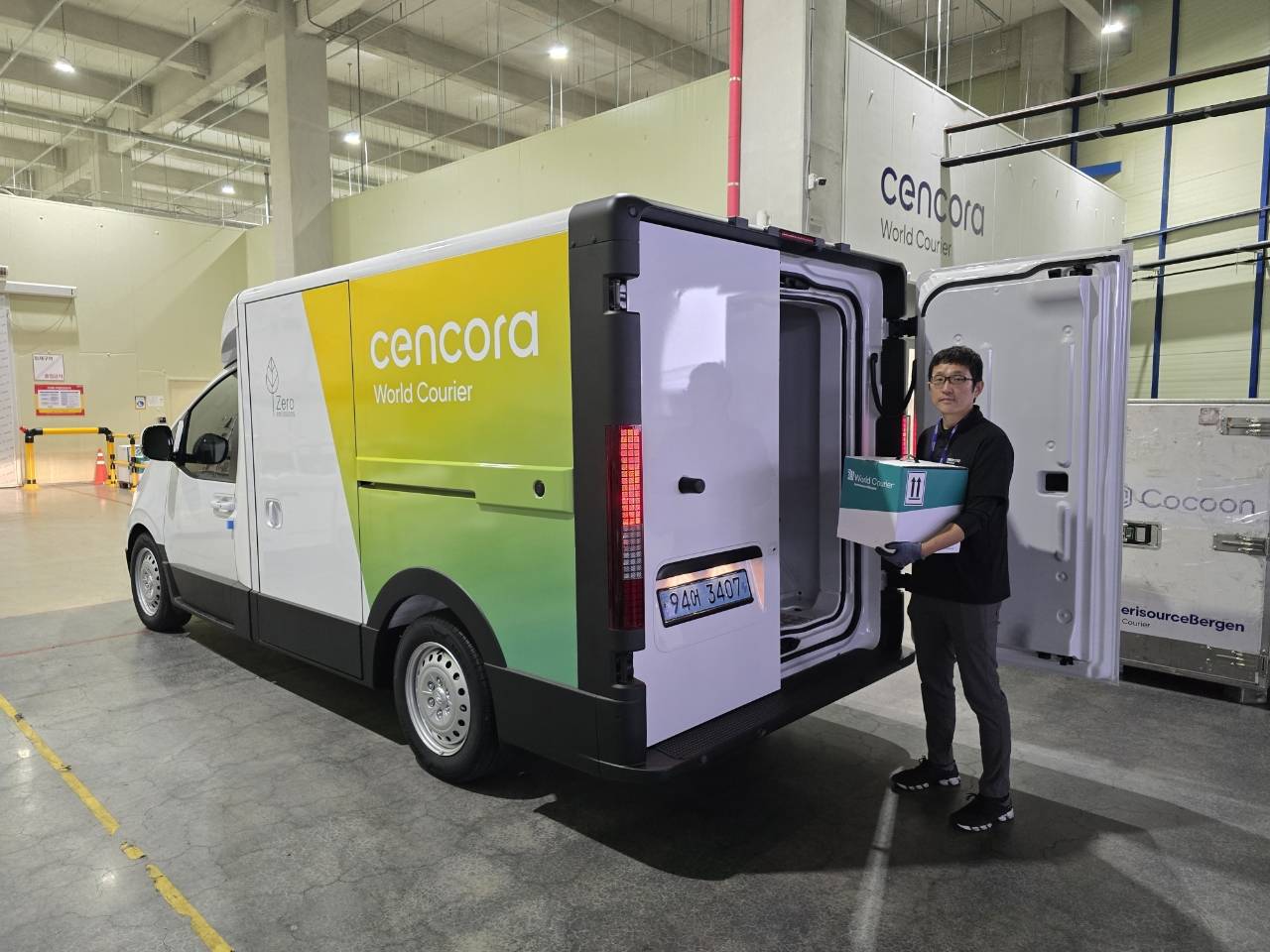 Picture of man holding box for delivery next to sustainable electric delivery van
