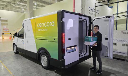 Picture of man holding box for delivery next to sustainable electric delivery van