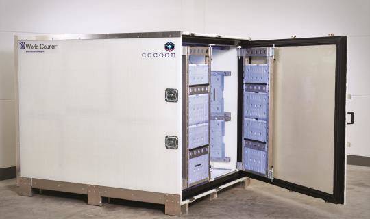 A cocoon shipping unit sits with its door open. Cooling gel packs are visible on the internal frame.