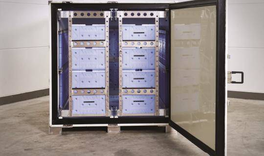 A cocoon shipping container with the door open, showing cooling gel packs in the internal frame.