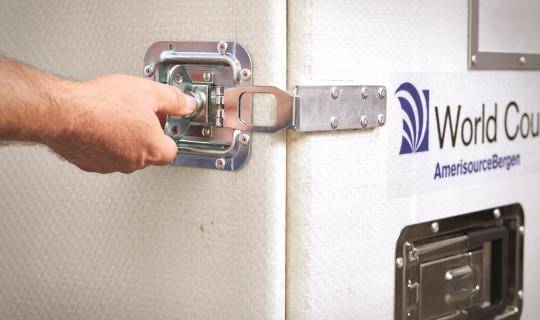 A hand reaches to unlatch a World Courier shipping container.