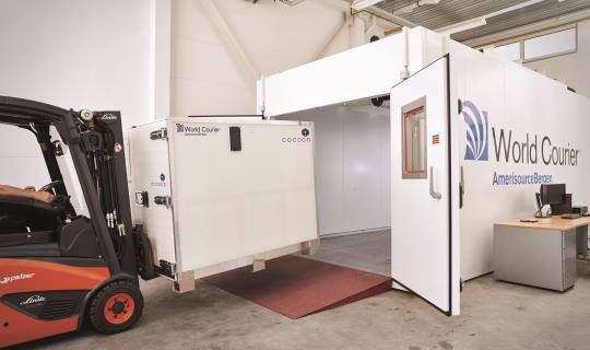 A forklift loads a Cocoon shipping container into a climate chamber at CORE Labs.