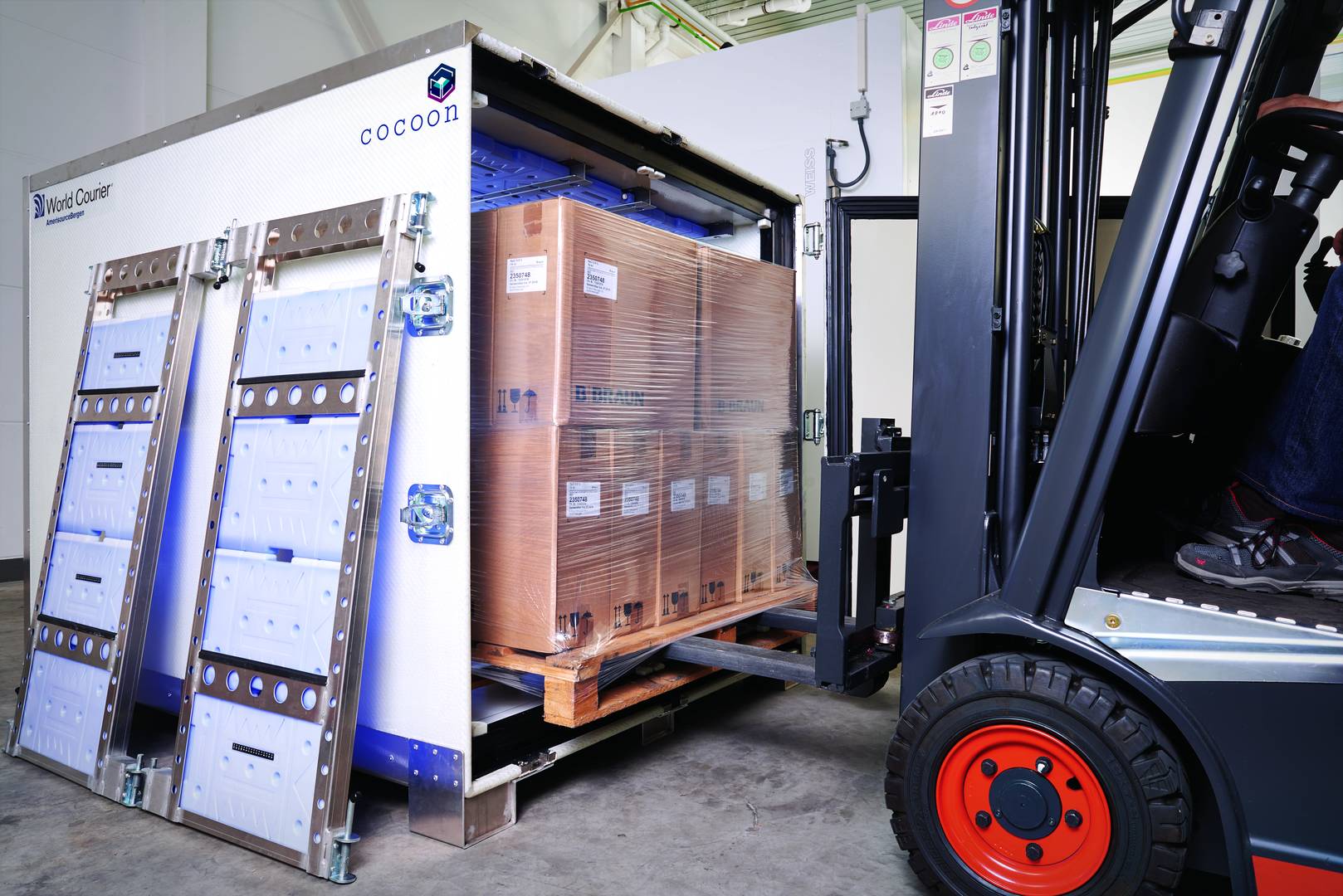 A forklift loads a pallet of boxes into a Cocoon shipping container.