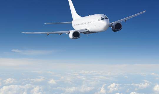 A wide view of an airplane flying over the clouds.