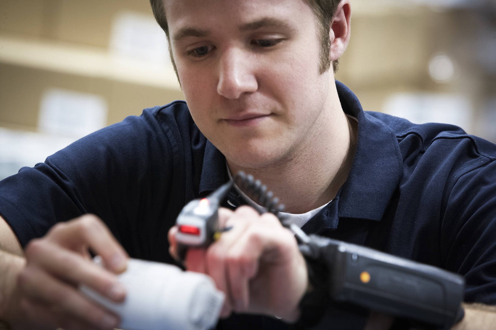 A man uses a handheld scanner to scan a barcode on a box of medication.